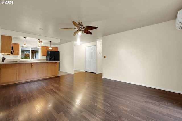 unfurnished living room featuring ceiling fan, a wall unit AC, and dark hardwood / wood-style floors