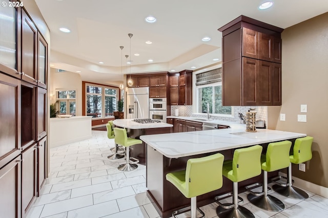 kitchen featuring decorative light fixtures, a center island, stainless steel appliances, and a breakfast bar