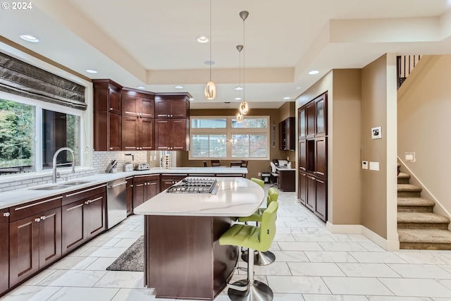 kitchen with sink, hanging light fixtures, a kitchen island, a kitchen bar, and stainless steel appliances