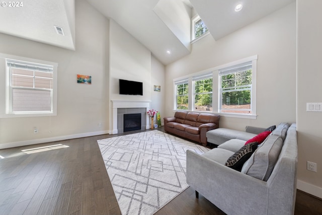 living room with dark hardwood / wood-style floors, high vaulted ceiling, and a tiled fireplace