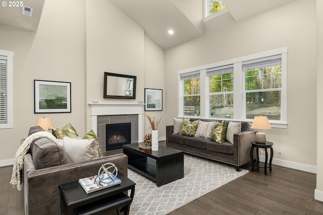 living room featuring a tile fireplace, hardwood / wood-style flooring, and high vaulted ceiling