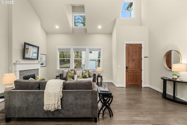 living room featuring hardwood / wood-style flooring, plenty of natural light, a towering ceiling, and a fireplace