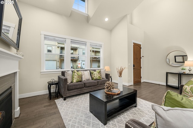 living room with a fireplace, dark wood-type flooring, and a high ceiling