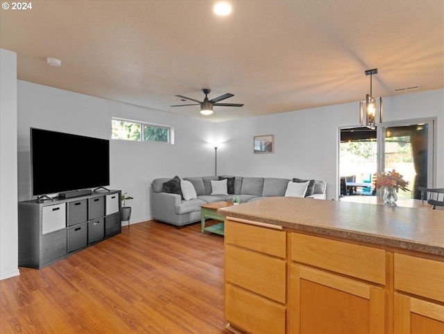 kitchen with ceiling fan with notable chandelier, light wood-type flooring, decorative light fixtures, and a wealth of natural light