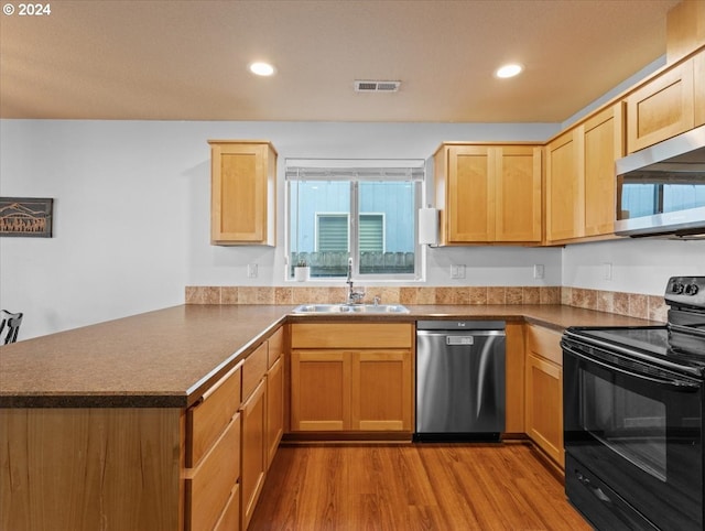 kitchen with sink, light wood-type flooring, light brown cabinetry, appliances with stainless steel finishes, and kitchen peninsula