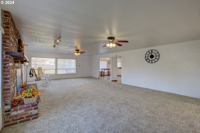 unfurnished living room with a fireplace, a textured ceiling, carpet floors, and ceiling fan