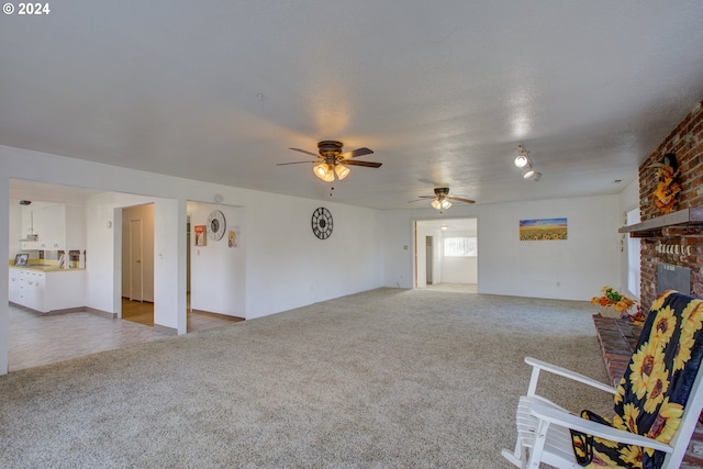 unfurnished living room with ceiling fan, light colored carpet, and a brick fireplace