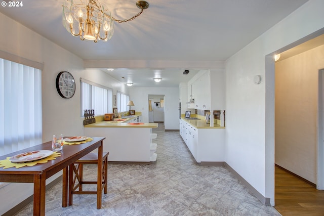 kitchen featuring kitchen peninsula, white cabinetry, and a notable chandelier