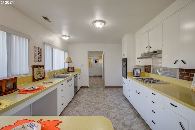 kitchen featuring white cabinets, appliances with stainless steel finishes, decorative backsplash, and sink