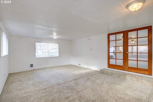 spare room with carpet flooring, plenty of natural light, and french doors