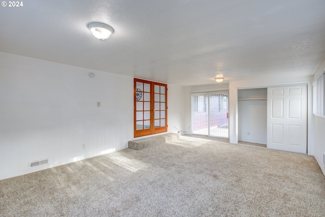 unfurnished room with carpet and a textured ceiling