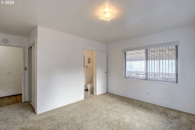 unfurnished bedroom featuring carpet, connected bathroom, and a closet