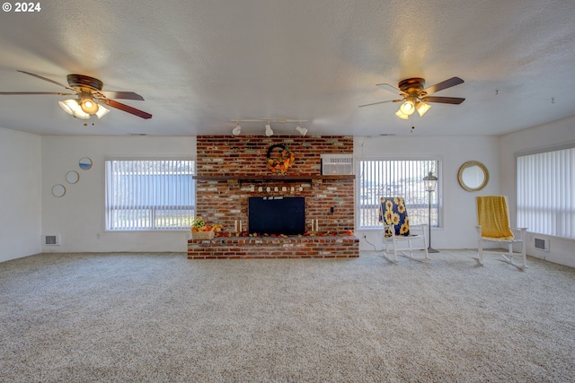 unfurnished living room with carpet flooring, track lighting, ceiling fan, and a brick fireplace