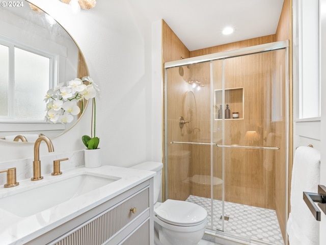 bathroom with vanity, toilet, and a shower with door