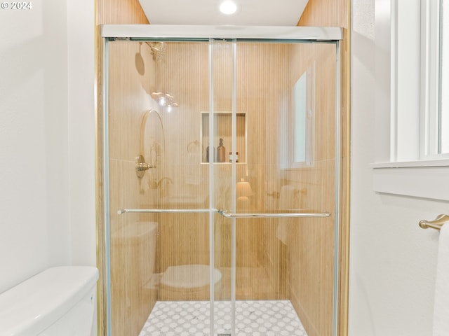 bathroom featuring toilet and a shower with shower door