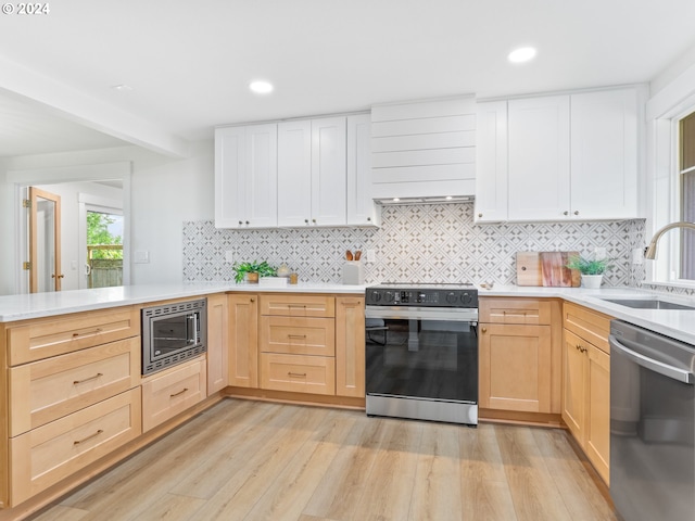 kitchen with appliances with stainless steel finishes, backsplash, light brown cabinets, and sink