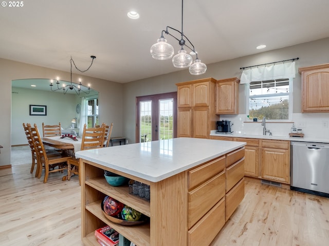 kitchen with light brown cabinetry, light wood-style floors, stainless steel dishwasher, and a sink