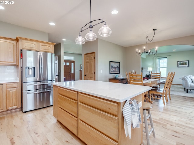 kitchen with light countertops, light wood finished floors, stainless steel refrigerator with ice dispenser, and light brown cabinetry