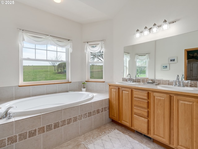 bathroom with a bath, double vanity, a sink, and visible vents