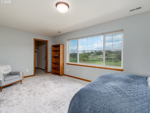 bedroom featuring a walk in closet, baseboards, carpet, and visible vents