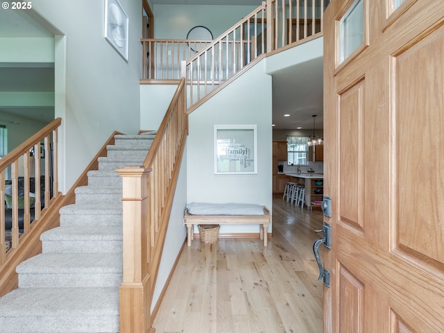foyer entrance featuring baseboards, stairway, a high ceiling, and wood finished floors