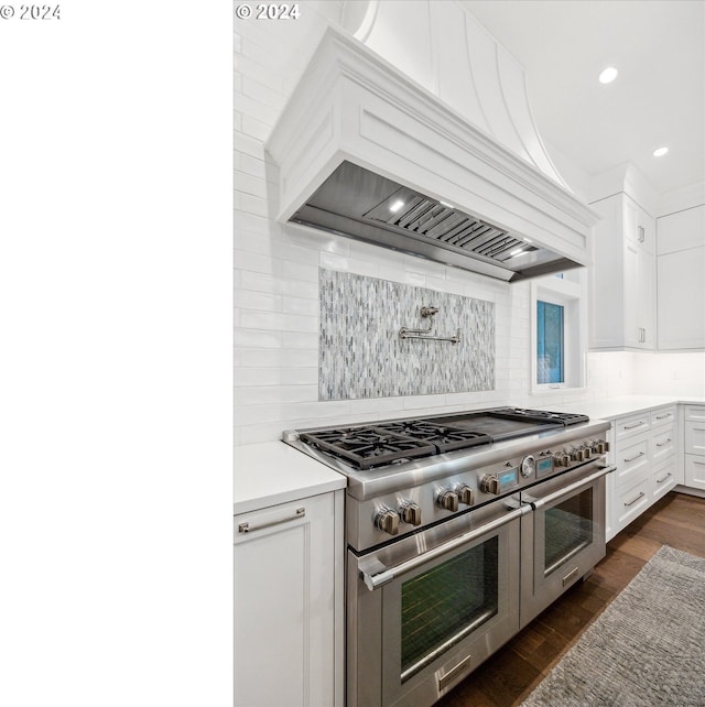 kitchen with custom exhaust hood, backsplash, dark wood-type flooring, white cabinets, and range with two ovens