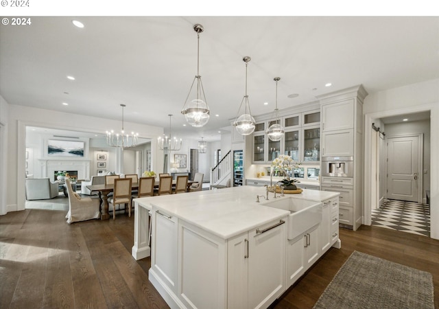 kitchen featuring a kitchen island with sink, white cabinets, dark hardwood / wood-style floors, and decorative light fixtures