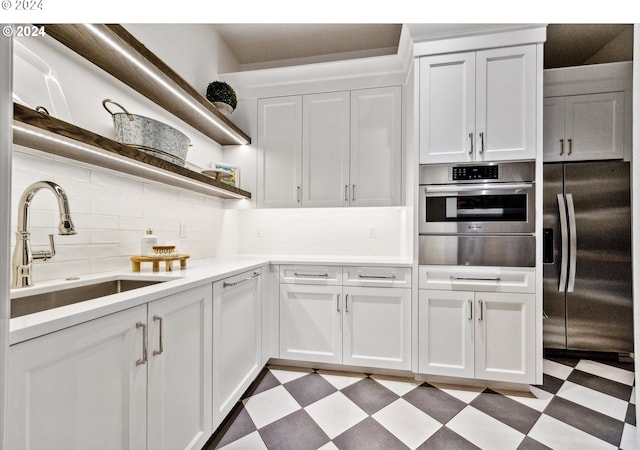 kitchen featuring a sink, stainless steel appliances, open shelves, a warming drawer, and dark floors