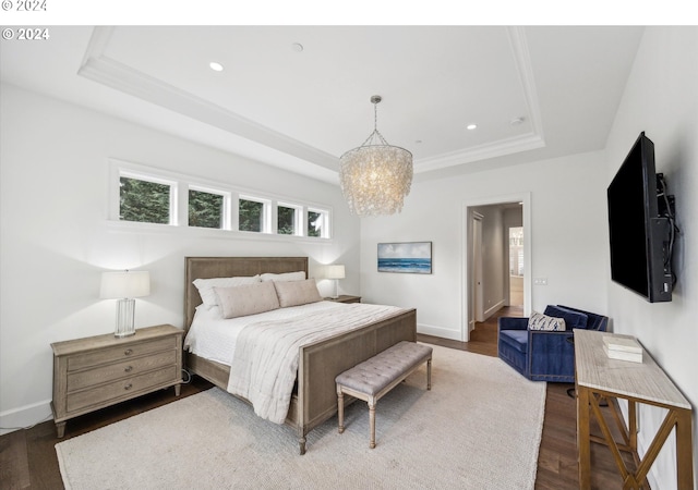 bedroom featuring recessed lighting, wood finished floors, an inviting chandelier, and a tray ceiling