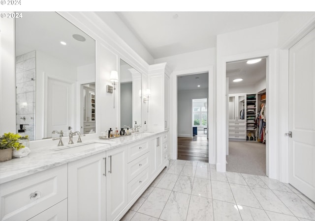 full bath featuring a walk in closet, marble finish floor, double vanity, and a sink