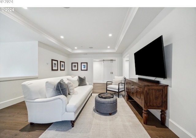 living room with a barn door, hardwood / wood-style flooring, crown molding, and a tray ceiling