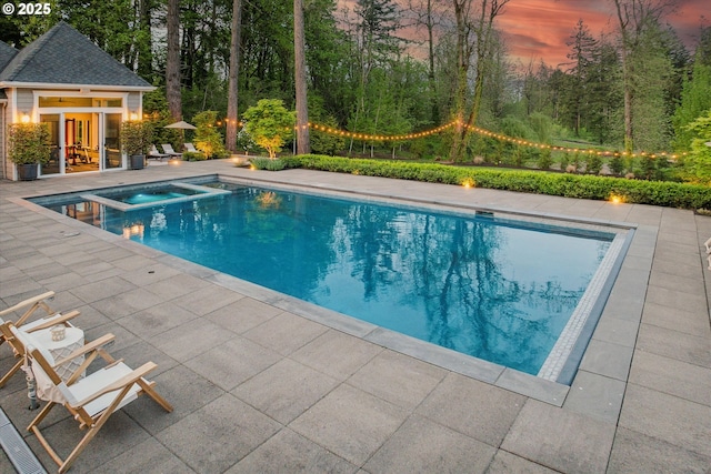 view of pool with a pool with connected hot tub, an outdoor structure, a storage structure, and a patio area