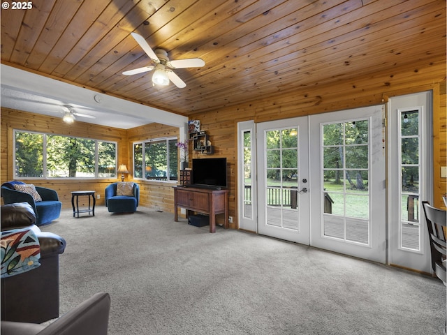 carpeted living room with french doors, wooden walls, a wealth of natural light, and wood ceiling