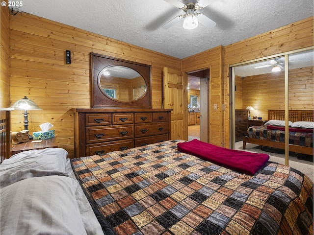 bedroom featuring a closet, ceiling fan, a textured ceiling, and wood walls