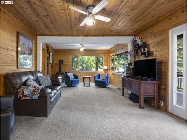 living room with carpet flooring, a wealth of natural light, wooden ceiling, and a wood stove