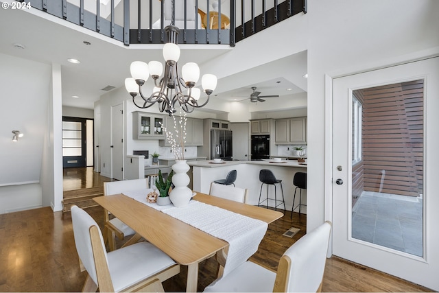 dining room featuring a high ceiling, ceiling fan with notable chandelier, and hardwood / wood-style flooring