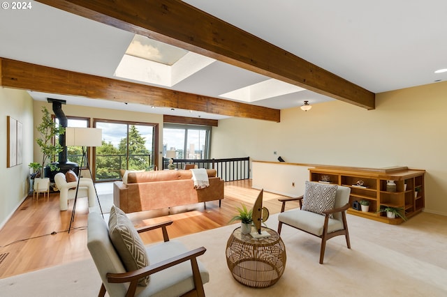 living room with a skylight, light hardwood / wood-style floors, and beam ceiling