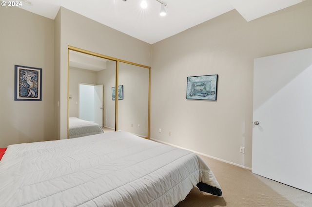 bedroom featuring rail lighting, a closet, and light colored carpet