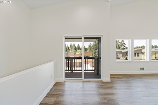 unfurnished room with high vaulted ceiling and wood-type flooring