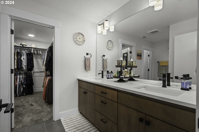 bathroom with tile patterned flooring, vanity, and a textured ceiling