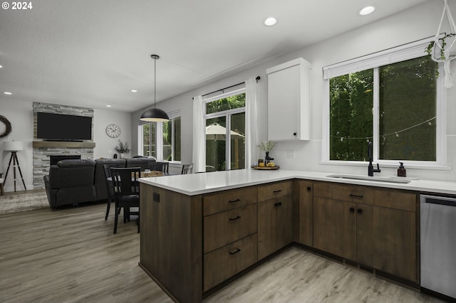 kitchen with dark brown cabinetry, dishwasher, sink, a fireplace, and white cabinets