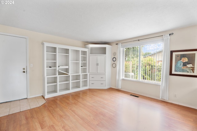 spare room featuring a textured ceiling and light hardwood / wood-style flooring