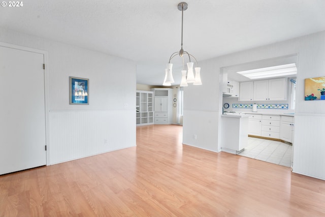 interior space with a textured ceiling, light hardwood / wood-style floors, and an inviting chandelier