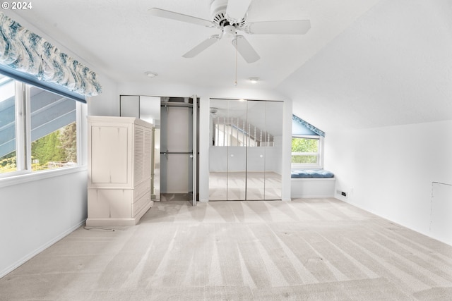 unfurnished bedroom with ceiling fan, light colored carpet, lofted ceiling, and multiple windows