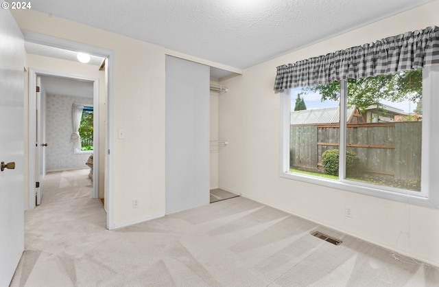 unfurnished bedroom with light carpet and a textured ceiling