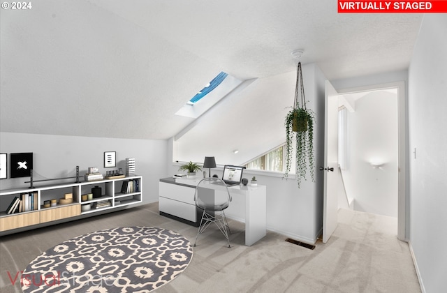 office space featuring vaulted ceiling with skylight and carpet