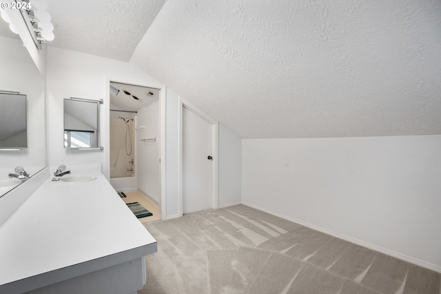 bathroom with vanity, shower / bathtub combination, a textured ceiling, and vaulted ceiling