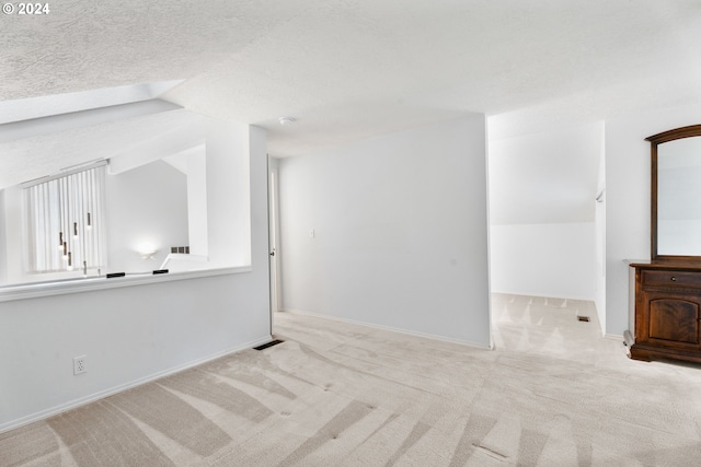 unfurnished living room with a textured ceiling, light colored carpet, and lofted ceiling