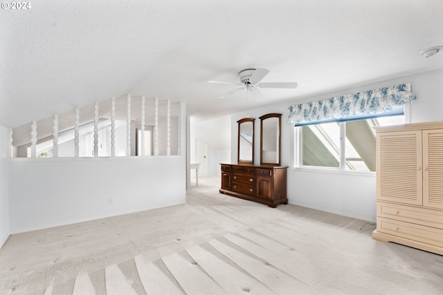 unfurnished bedroom featuring light colored carpet, vaulted ceiling, and ceiling fan