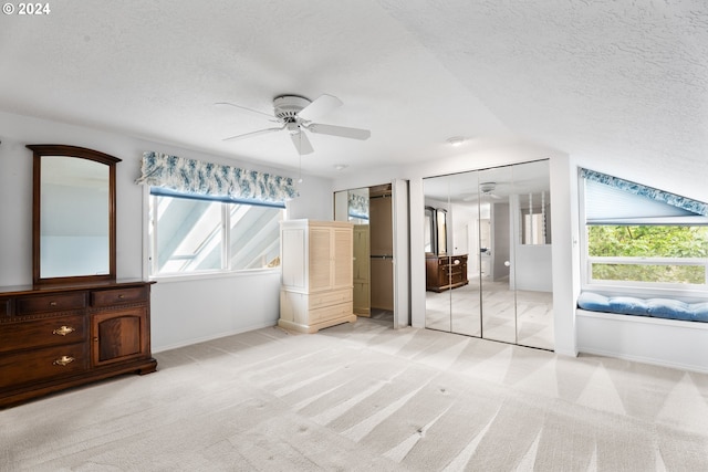 unfurnished bedroom featuring ceiling fan, lofted ceiling, light carpet, and multiple windows